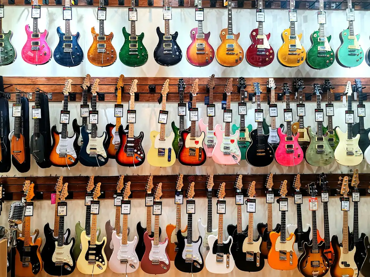 Client essayant une guitare acoustique en magasin spécialisé avec l'aide d'un vendeur