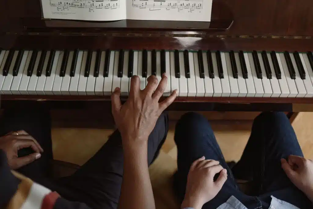 Mains d'un élève sur les touches du piano lors d'un cours de musique en studio lumineux