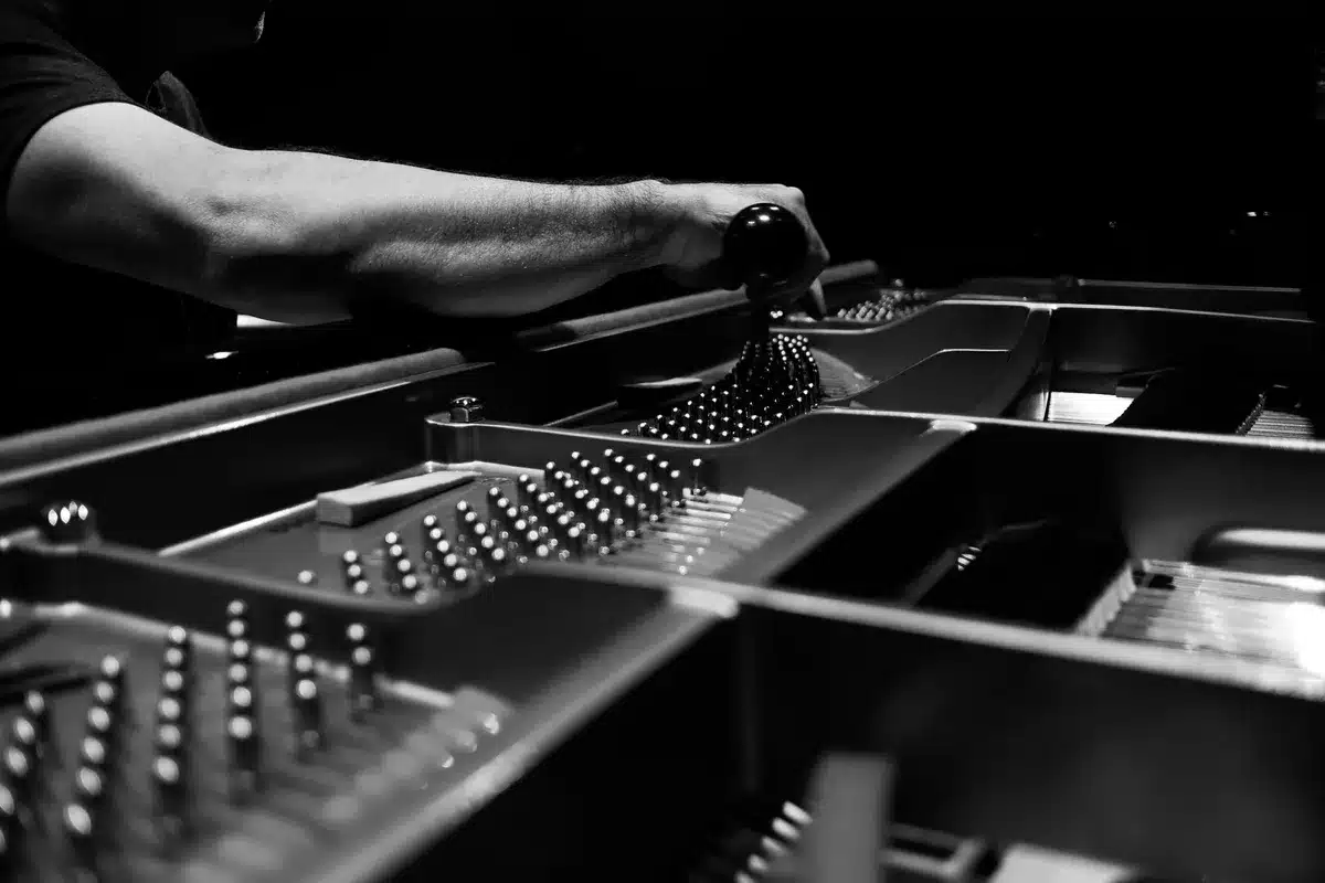 Technicien examinant l'intérieur d'un piano pour vérifier l'état mécanique