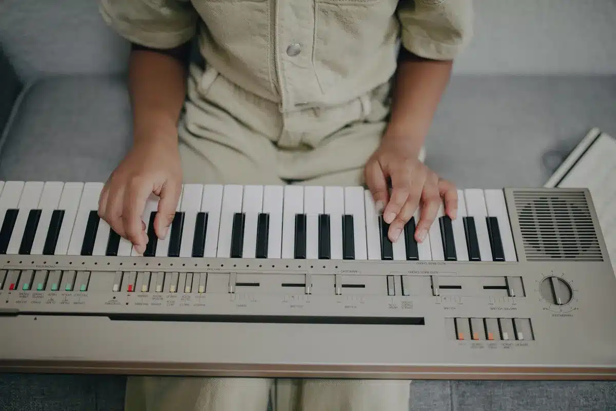 Mains d'une personne jouant d'un instrument dans un salon lumineux avec des partitions et un carnet de travail
