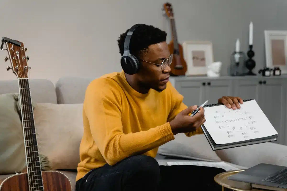 Musicien transcrivant un morceau à l'oreille avec casque et carnet de notes