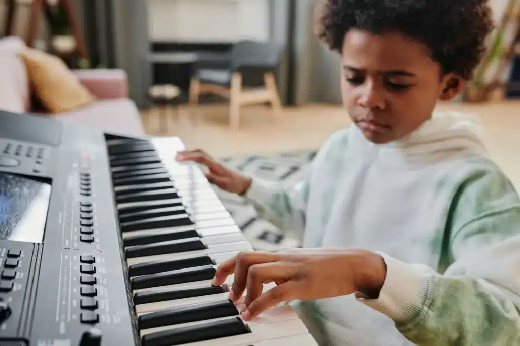 Les mains d'un enfant sur les touches d'un piano en séance d'apprentissage