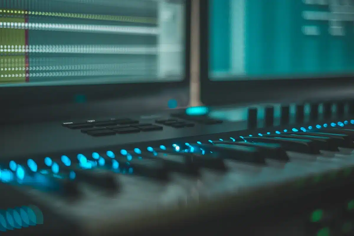 Mains manipulant boutons et curseurs d'un synthétiseur métallique en studio