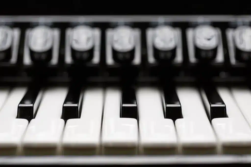 Clavier de piano en plein jour avec une main anonyme pointant vers le groupe de deux touches noires