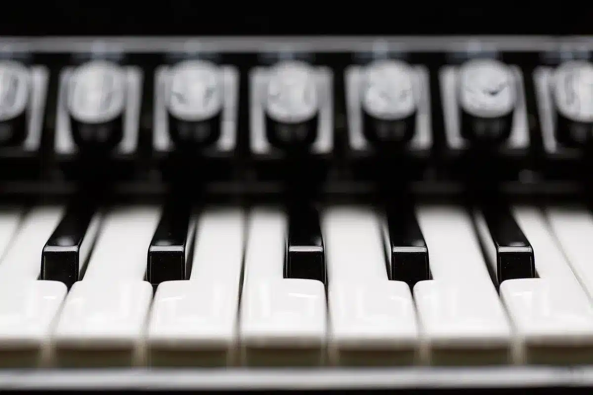 Clavier de piano en plein jour avec une main anonyme pointant vers le groupe de deux touches noires